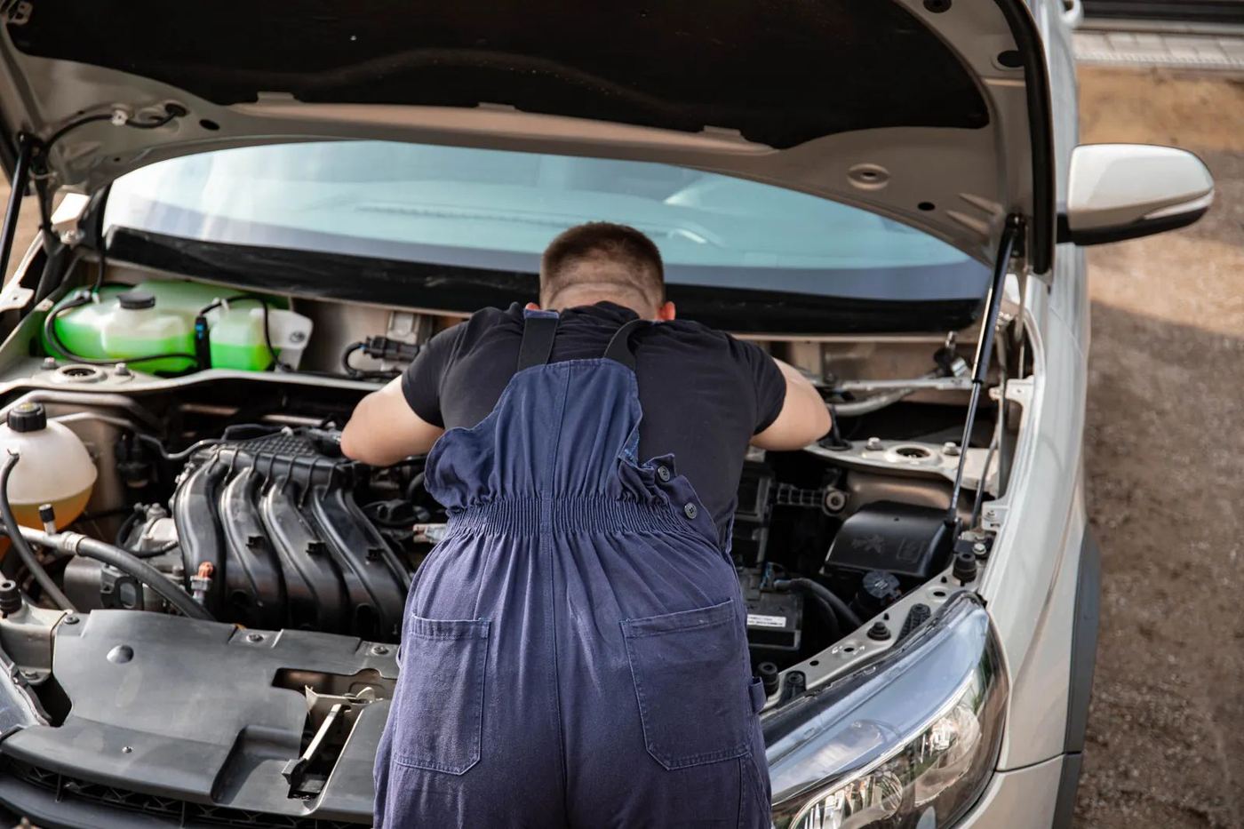 An ARS mechanic leaning into an open engine bay at work
